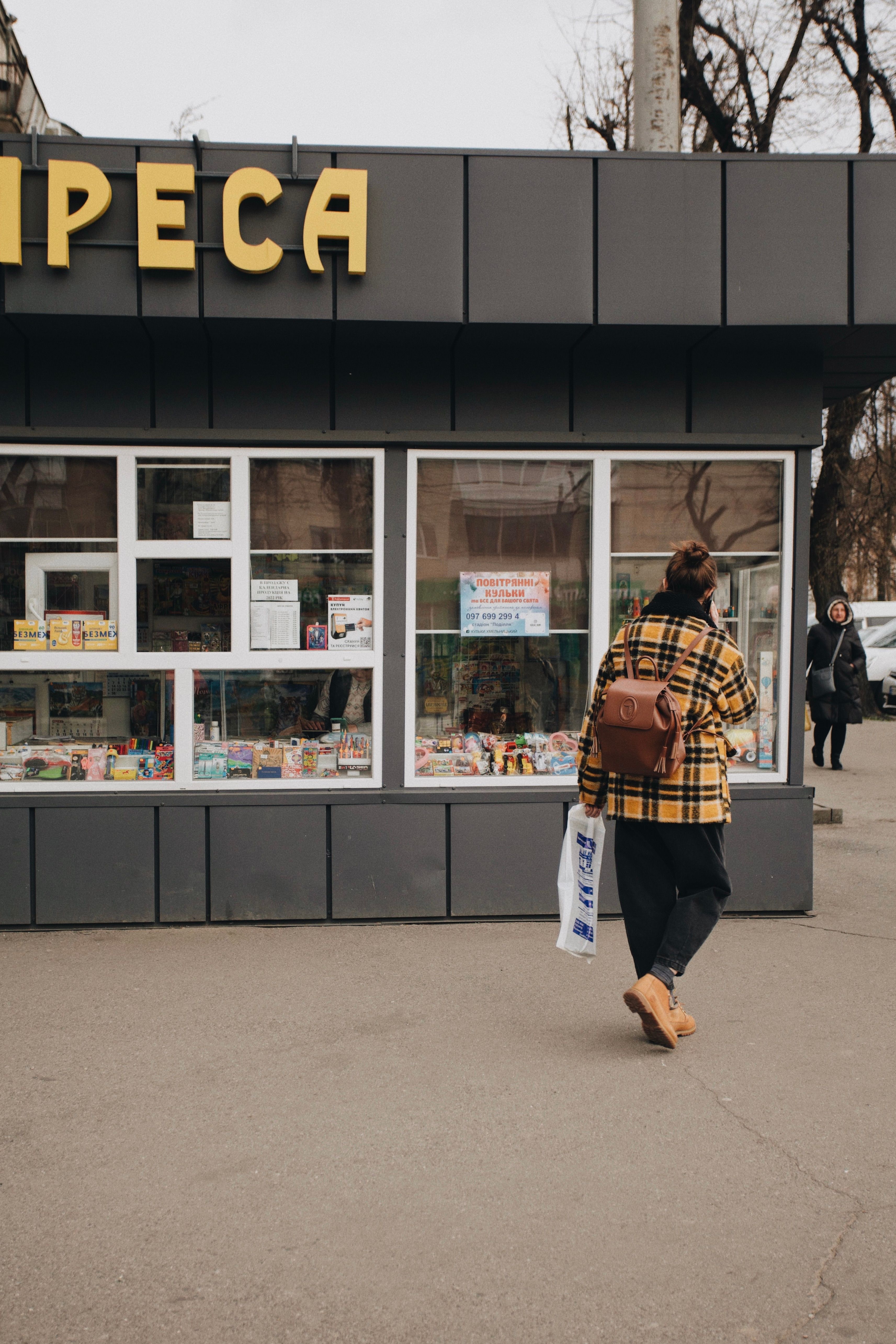 Woman Walking in Front of a Newsstand · Free Stock Photo