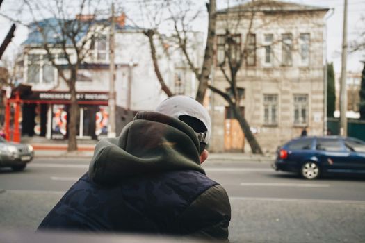 A man in a hoodie stands on a street in Ukraine, showcasing urban life.