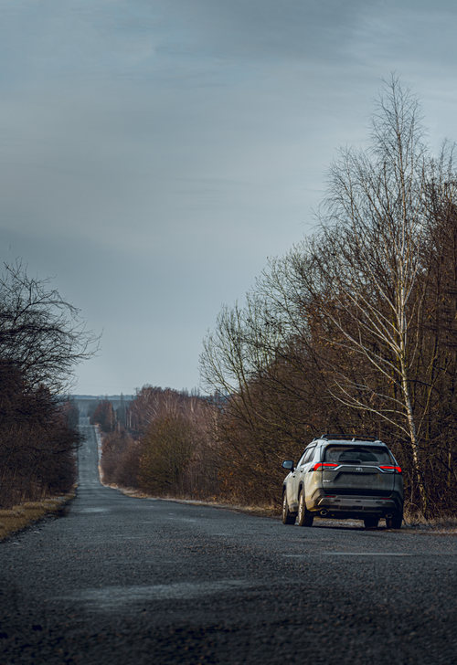 Free A lone SUV on an empty road surrounded by bare trees in a wintery rural Ukraine setting. Stock Photo