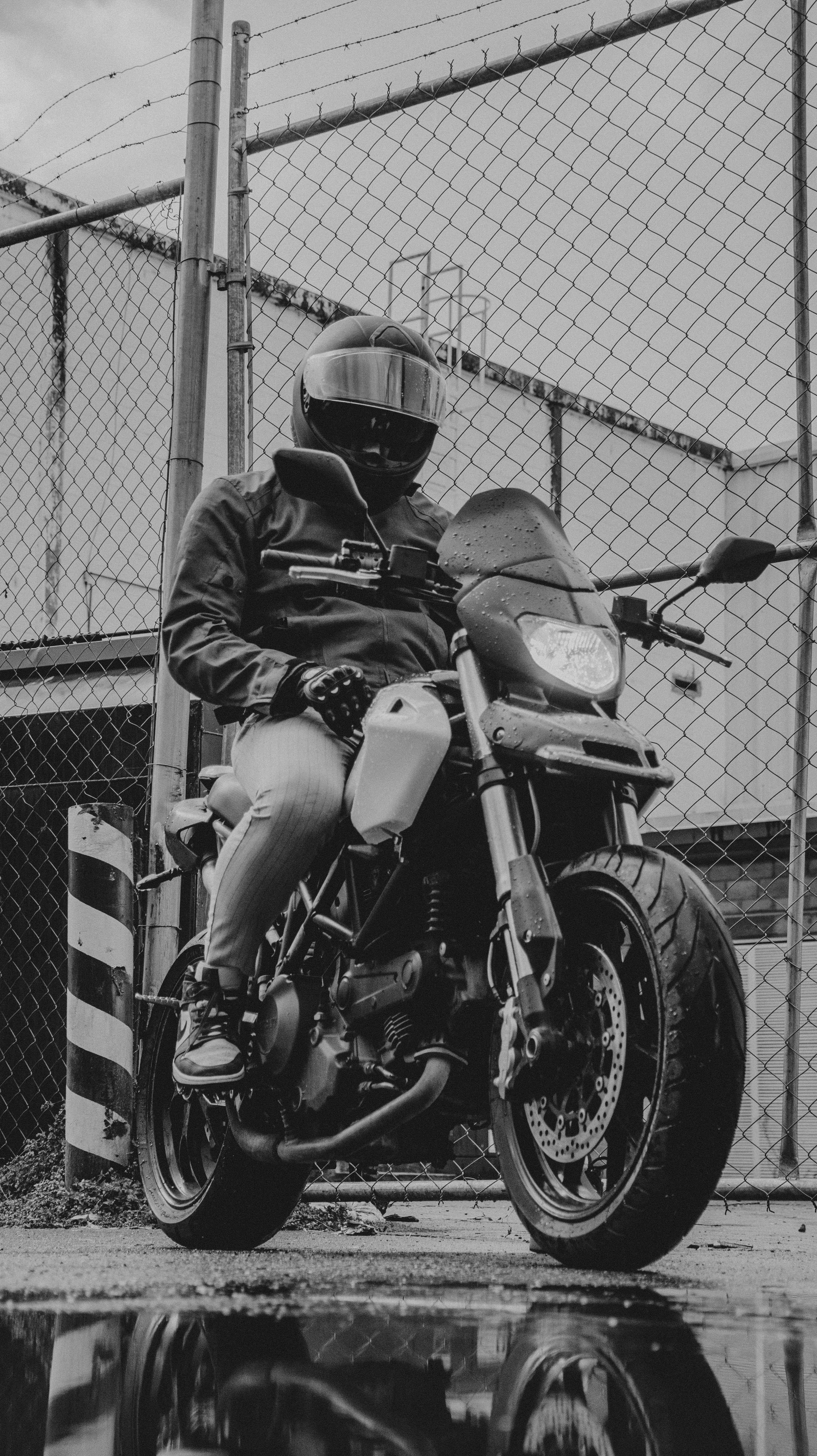 Free A motorcyclist seated on a motorcycle in an urban setting, captured in monochrome tones. Stock Photo