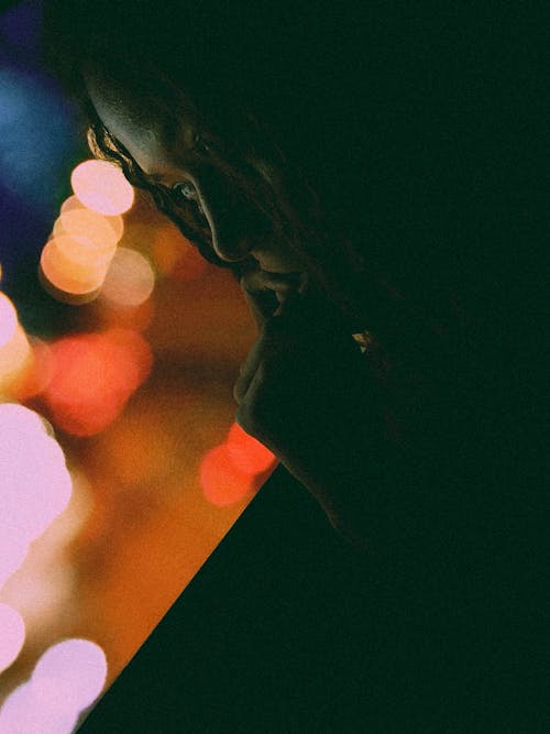 Close-Up Shot of a Person Looking Lonely Against Bokeh Lights