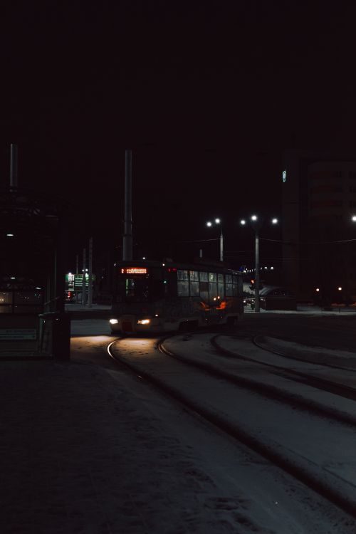 Free Tramway on a snowy street in a city under a dark sky, brightened by street lights. Stock Photo
