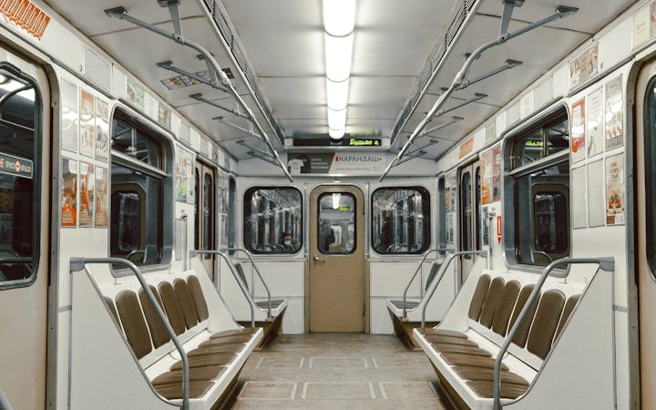 A wide-angle view of a clean and empty subway train interior with rows of seats.