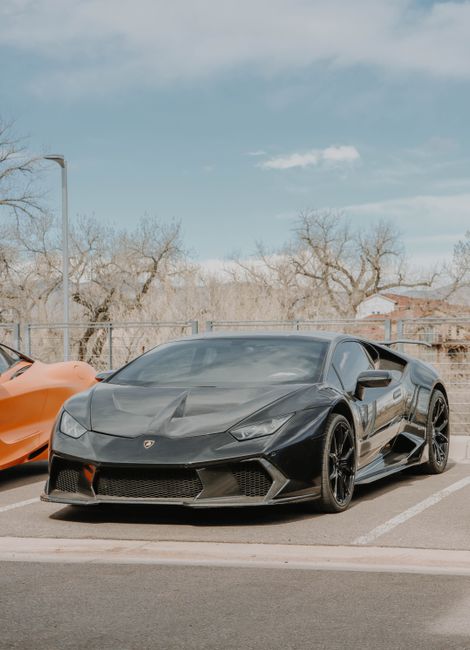 Black Lamborghini sports car parked outdoors, showcasing luxury design.