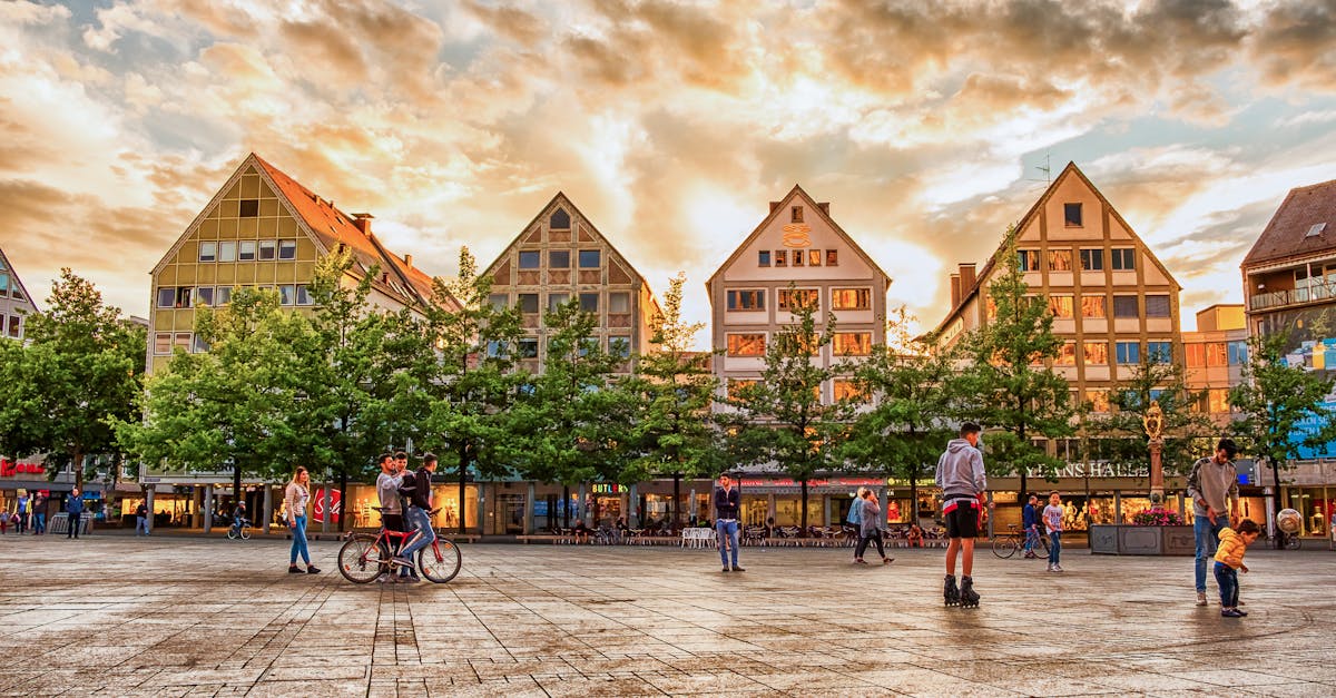 A vibrant town square in Ulm, Germany, with people enjoying the sunset.