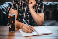桌上放着一杯可乐，一名男子正伏案写字