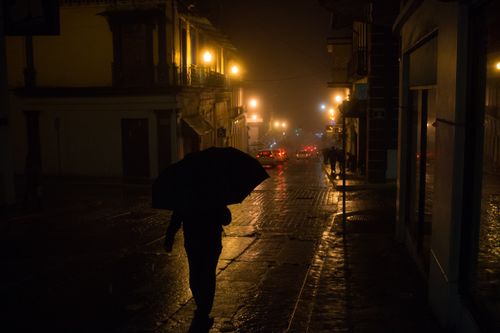 Free Silhouette of a person with an umbrella walking on a wet street at night in Xalapa, Mexico. Stock Photo