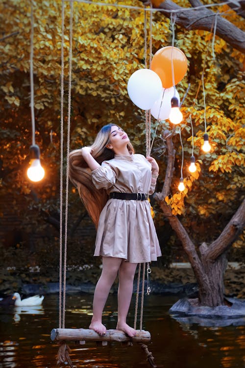 A Pretty Woman Standing on a Swing Flipping Her Hair