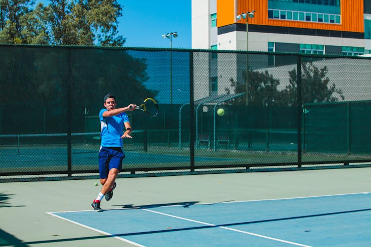 A Man Hitting A Tennis Ball