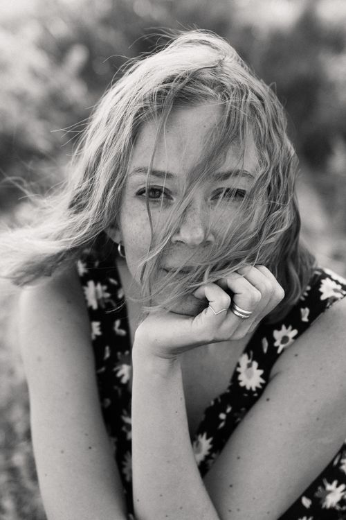 Free Black and white portrait of a woman in a floral dress, hand on chin, outdoors. Stock Photo