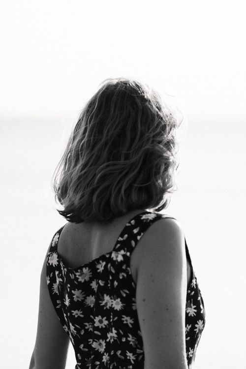 Free Monochrome photo of a woman in a floral dress viewed from behind, evoking stylish elegance. Stock Photo