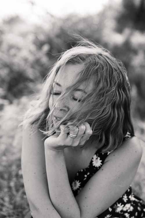 Free Captivating black and white portrait of a woman in a floral dress, lost in thought outdoors. Stock Photo