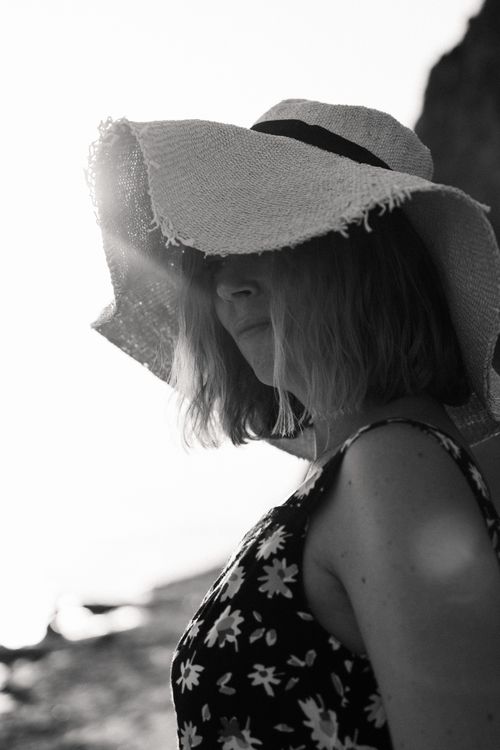 Free Black and white portrait of a woman in a straw hat by the beach, capturing summer elegance. Stock Photo