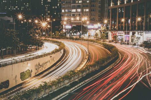 Beautiful nighttime city scene capturing vibrant light trails on a curved expressway.