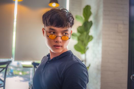 室内，一名戴着时髦墨镜的年轻人自信地看向旁边