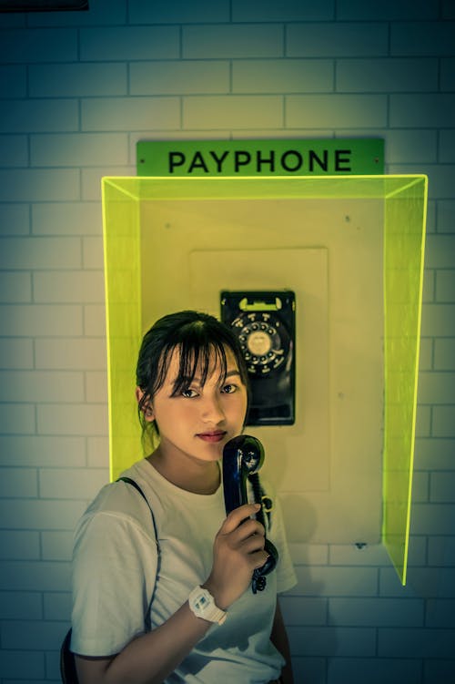 Woman in White Shirt Holding Telephone