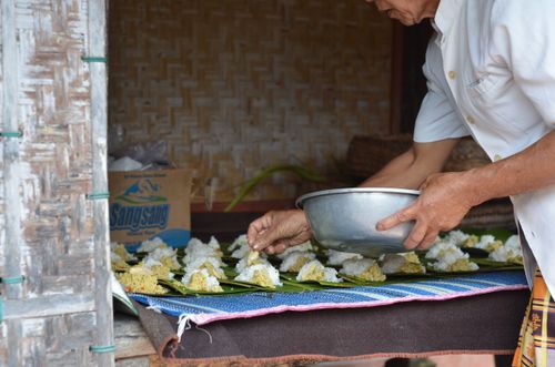 Free Person preparing traditional rice offerings with banana leaves in Bali. Stock Photo