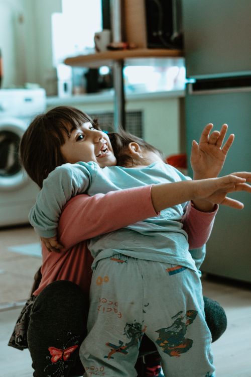 Free Two young siblings joyfully embracing in a cozy indoor setting. Stock Photo