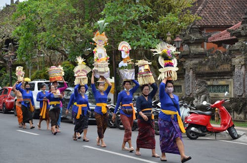 Balinese Women Walking in a Procession on a Street and Carrying Objects on Their Heads