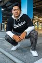 Man in Black and White Hoodie Sitting on Gray Concrete Floor