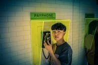 一名年轻人站在室内的付费电话前