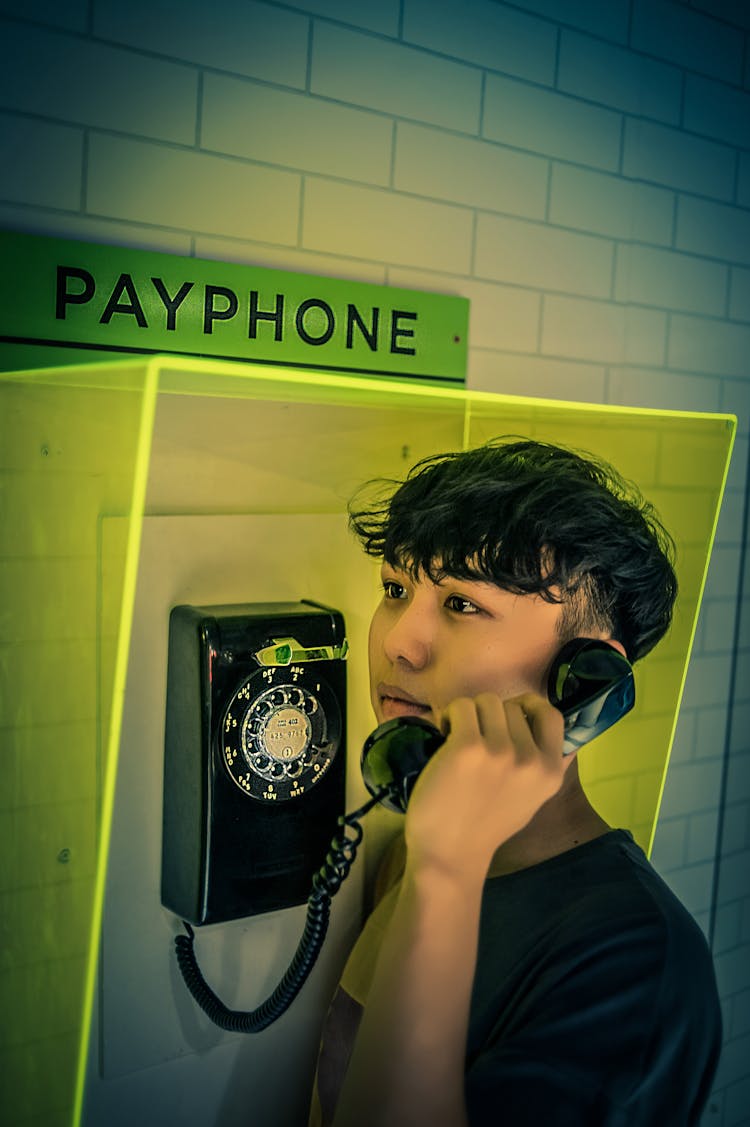 Man Holding Black Rotary Payphone