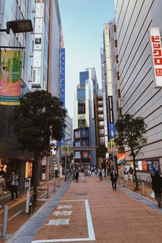 Vibrant street view in Shibuya, Tokyo with people, shops, and colorful banners.