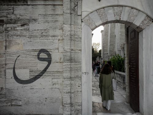 Free Tourists walk through an ancient archway in Istanbul, capturing the essence of Turkish architecture. Stock Photo