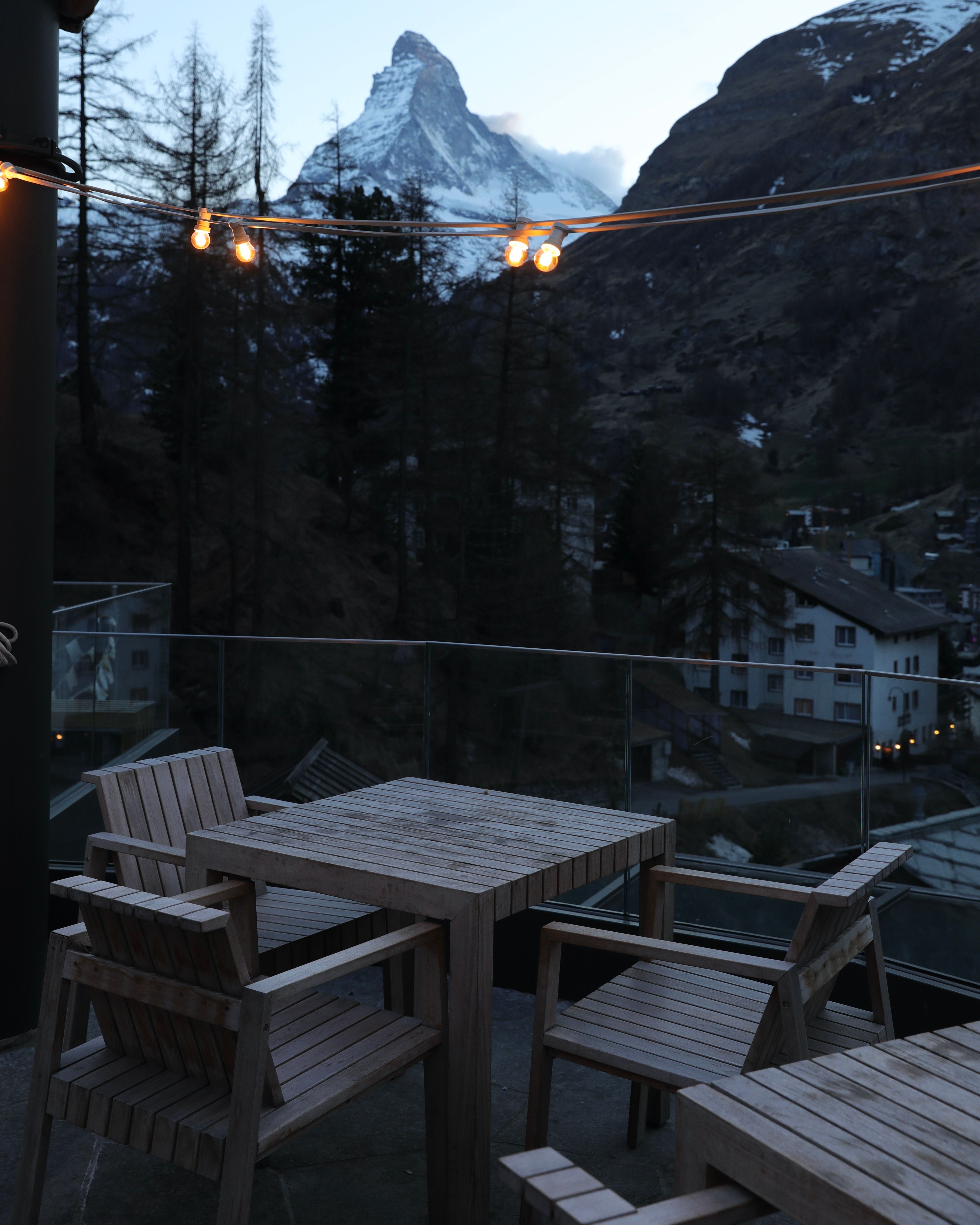 Cozy winter patio with wooden furniture and mountain view, ideal for relaxation.