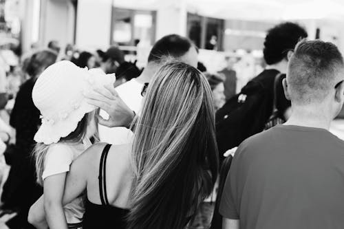 Woman Carrying a child Wearing a Sun Hat standing next to a man