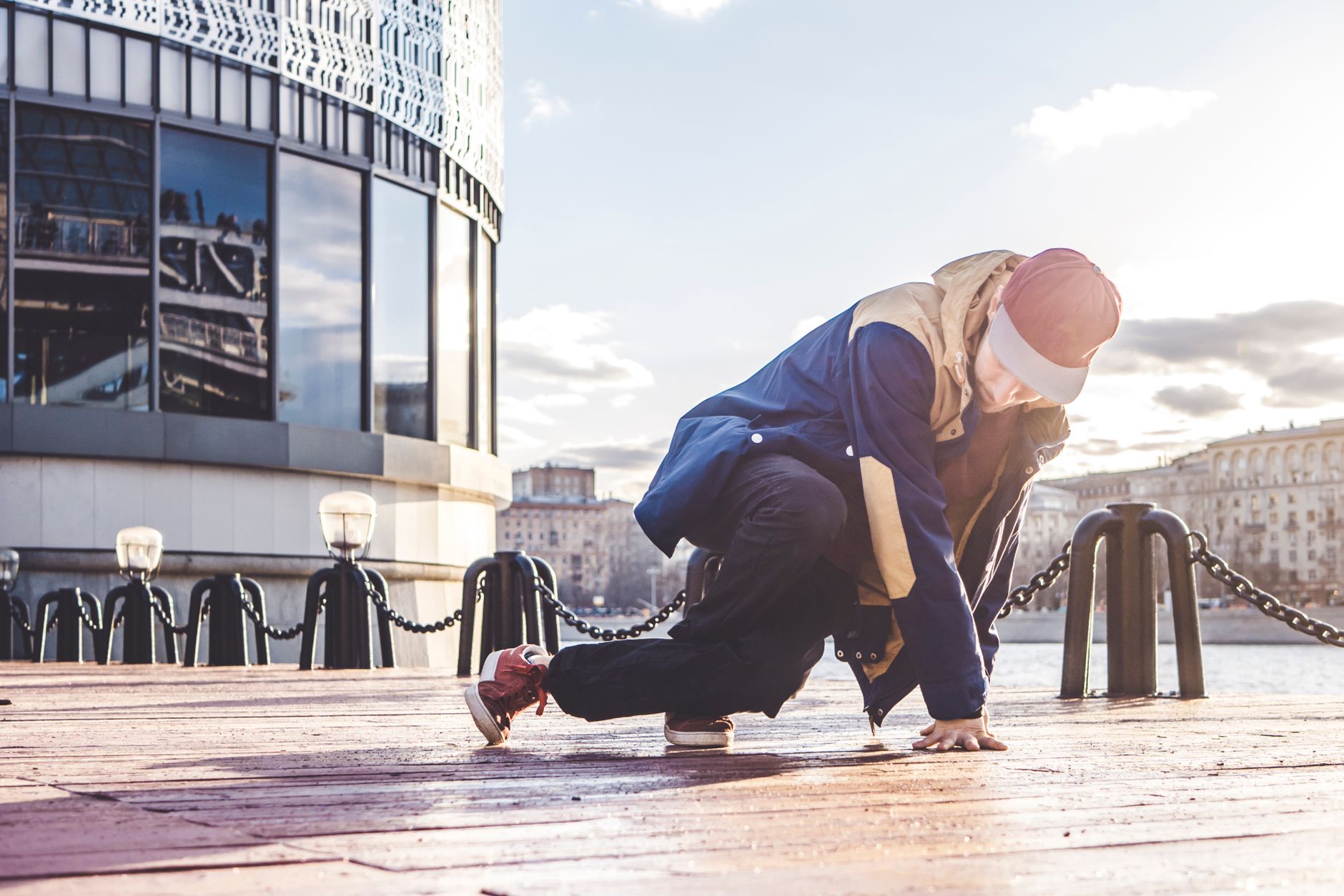 A young male dancer in streetwear breakdancing outdoors in an urban setting.