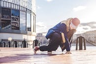 在城市环境中，一位穿着街头服饰的年轻男舞者正在户外跳霹雳舞