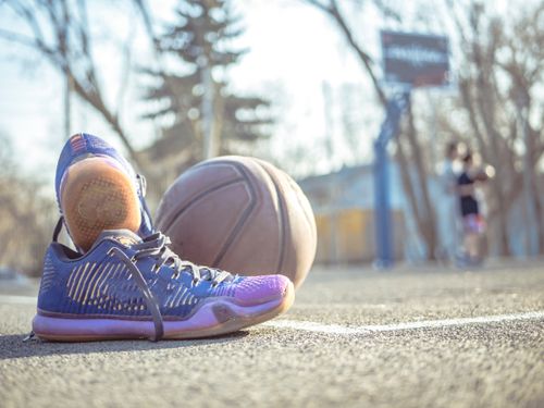 Free Detailed shot of sneakers next to a basketball on an outdoor court. Stock Photo