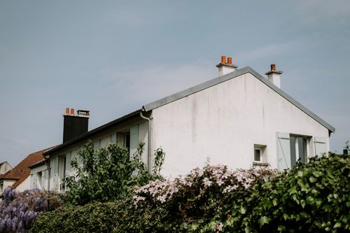 Free Rustic cottage with a pitched roof and blooming flowers against a clear sky. Stock Photo