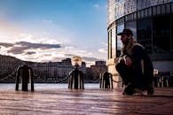 日落时分，一个人跪在城市河边的码头上，背景是现代建筑