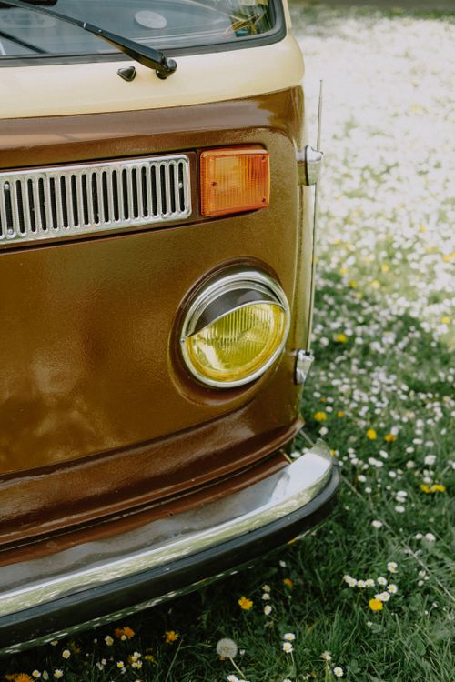 Free Close-up of a vintage car's headlight in a vibrant field of daisies, capturing a nostalgic vibe. Stock Photo
