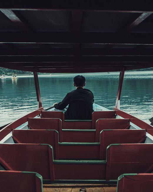 Man enjoys a quiet, solitary boat ride on Rancabali Lake, Jawa Barat, Indonesia, surrounded by nature.