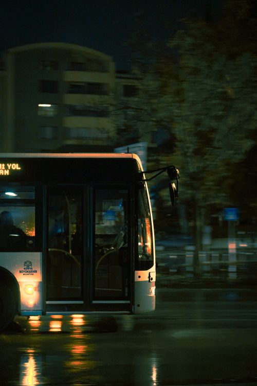 Free A city bus captured in motion at night, reflecting on a wet urban street. Stock Photo
