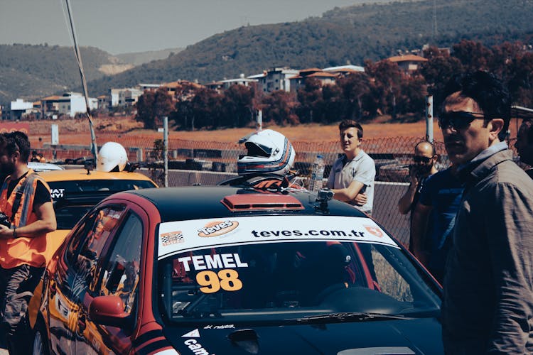 People Standing Around A Car