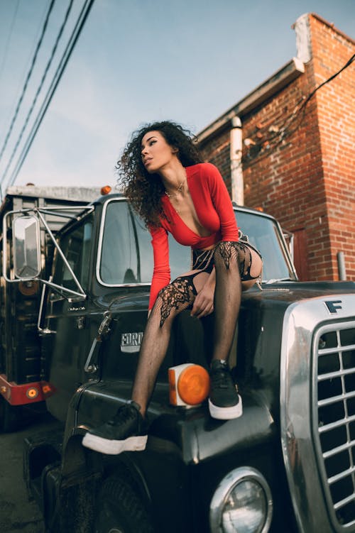 A Sexy Woman Sitting on the Hood of a Truck