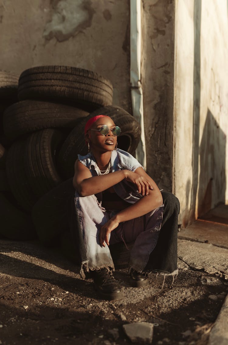 Woman Crouching Next To Stack Of Old Tires