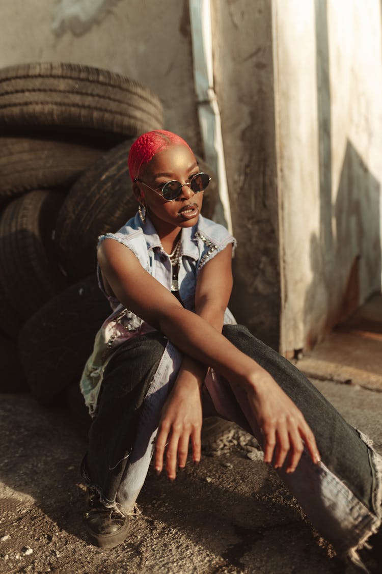 Woman With Dyed Hair Sitting Next To Stack Of Old Tires