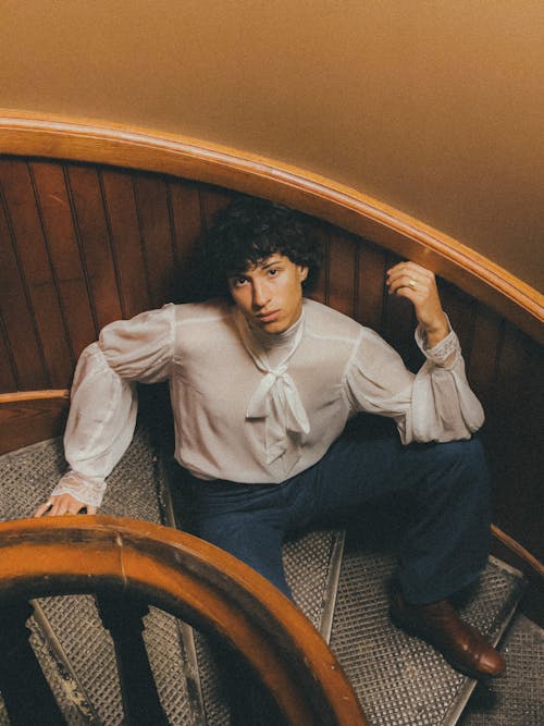 Free Teenage Boy Sitting on Vintage Spiral Staircase Stock Photo