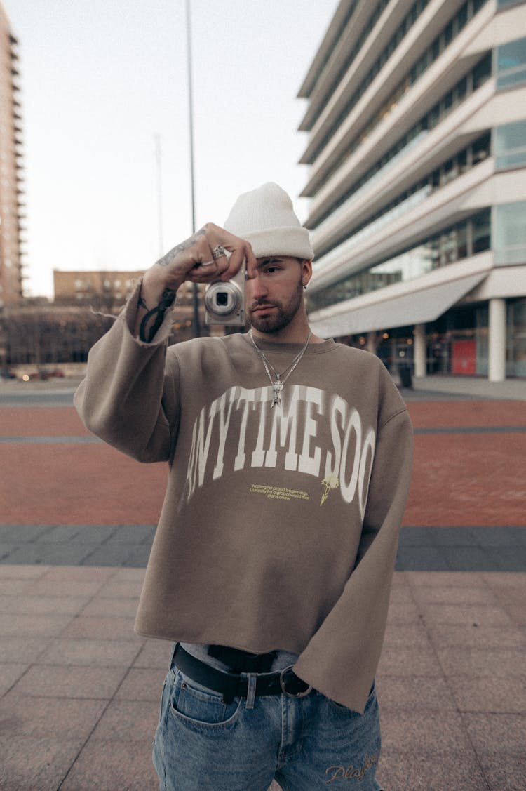 Young Man In White Knitted Hat Taking Shot With Photo Camera 