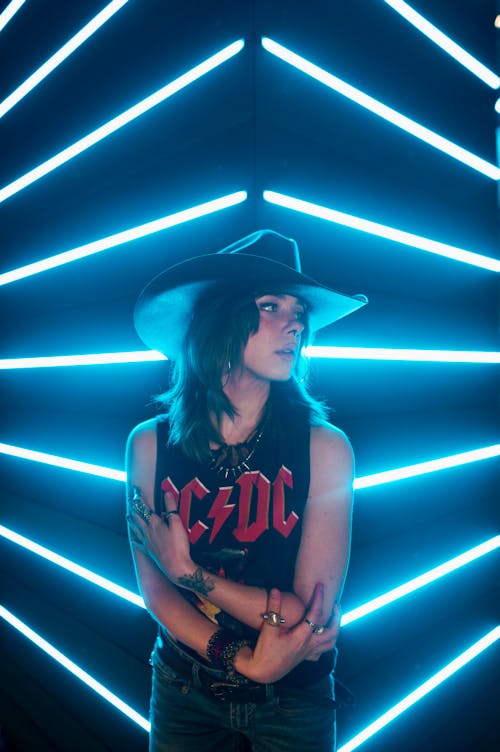 Young Woman in Cowboy Hat with Blue Neon Lights in Background