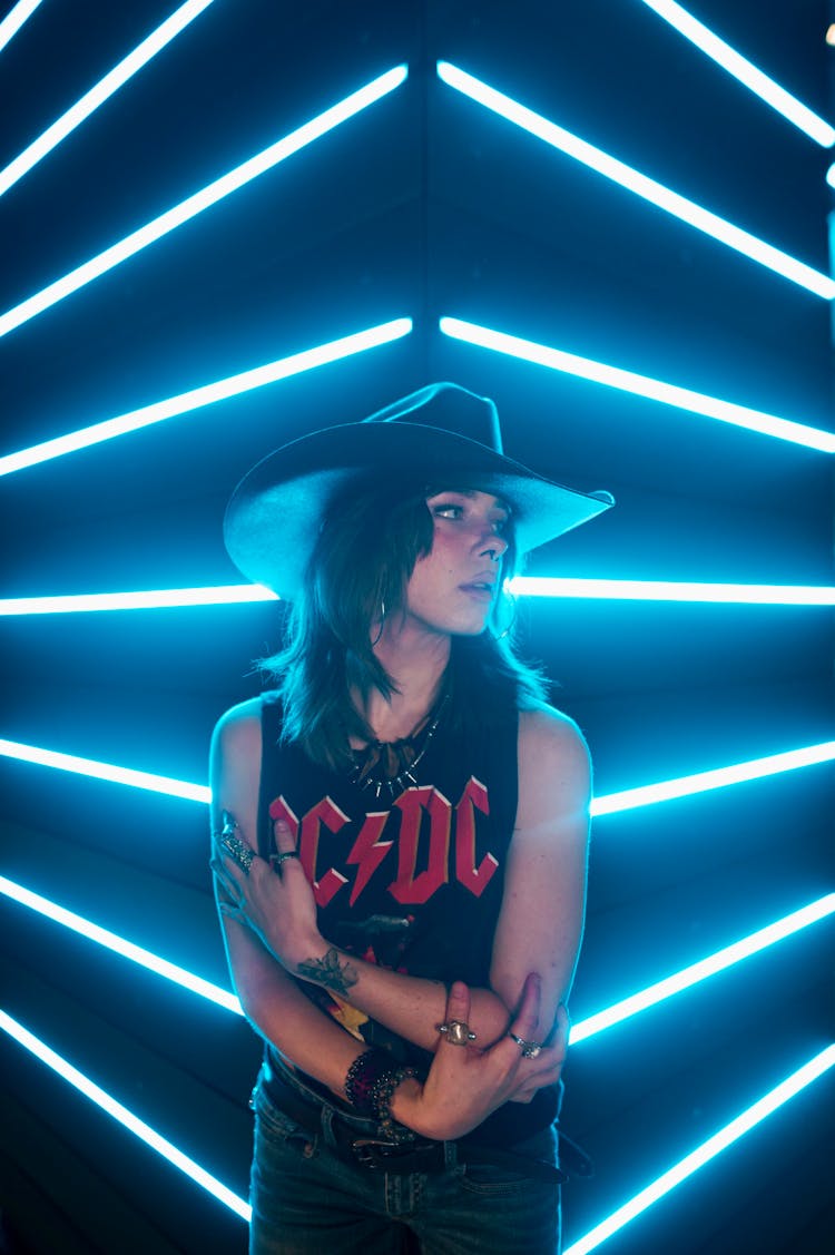 Young Woman In Cowboy Hat With Blue Neon Lights In Background