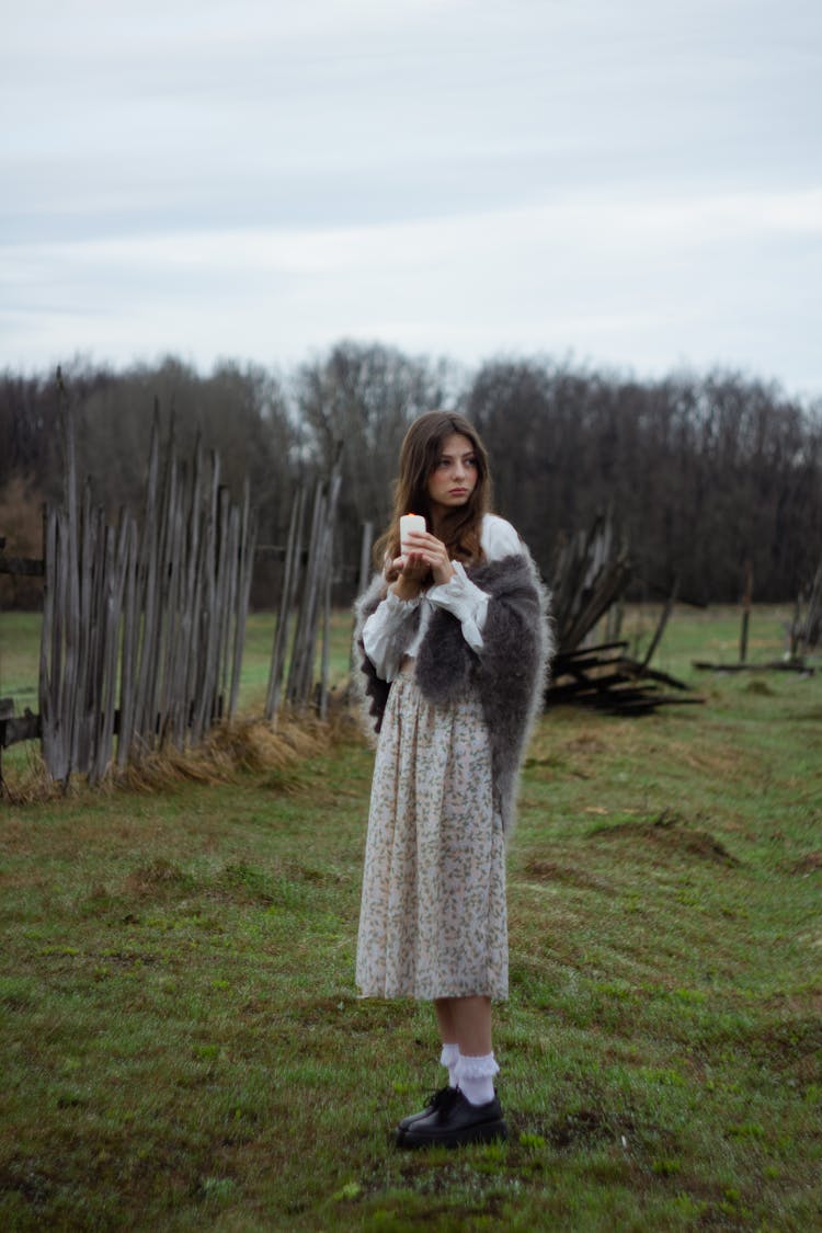 Woman In Gray Fur Shawl Standing On Green Grass Field