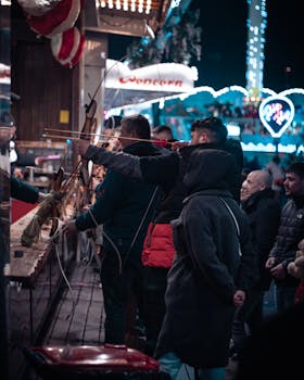 Vibrant night market scene with people engaging in archery games under neon lights.