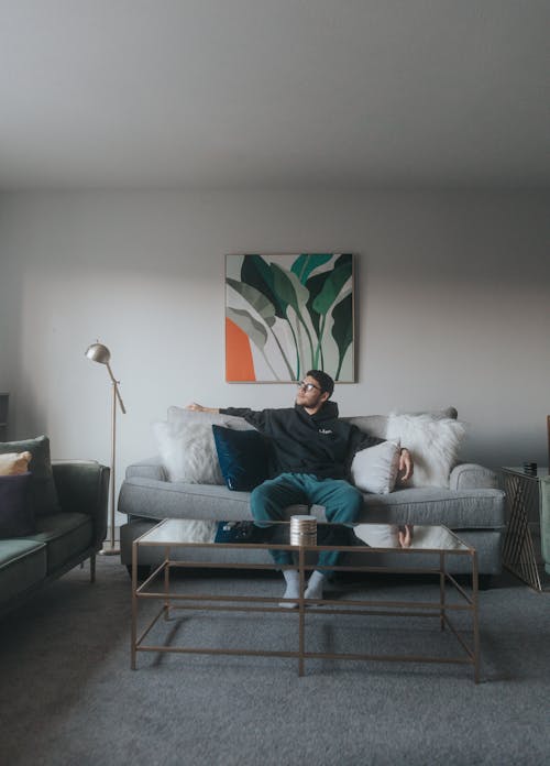 A Man in Hoodie Sweater Sitting on a Couch while Looking Afar