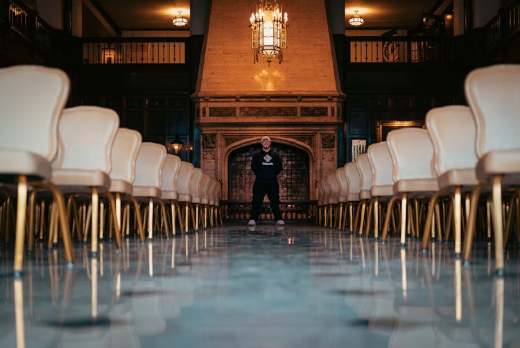 Man Standing At End Of Aisle Between Rows Of Seats